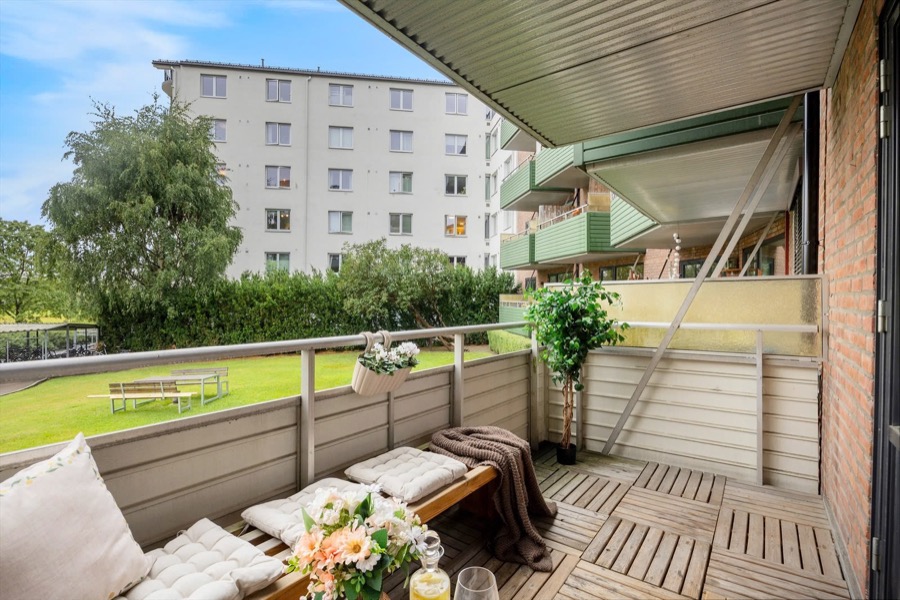 Balkong med sitteplass, blomster og grønne omgivelser