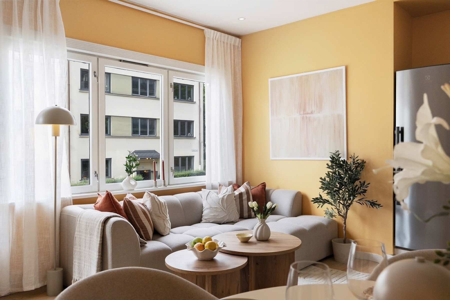 Bright living room with yellow walls, a sofa and round coffee tables