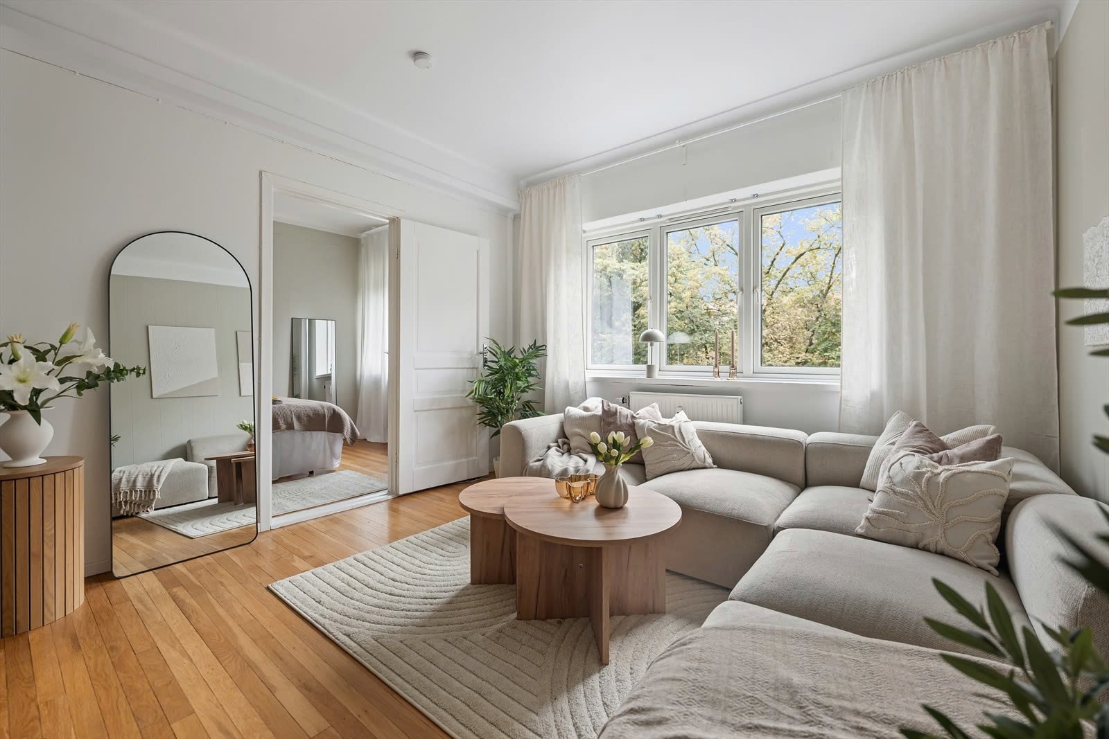 Bright living room with a sofa, large window and warm wooden floors